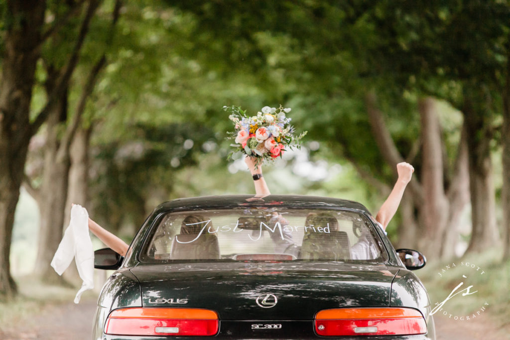 bride and groom driving away with bouquet out of sunroof