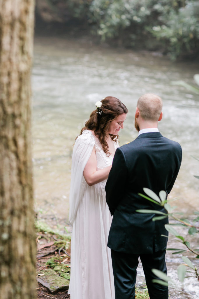 Bride and groom read vows to each other privately by a stream