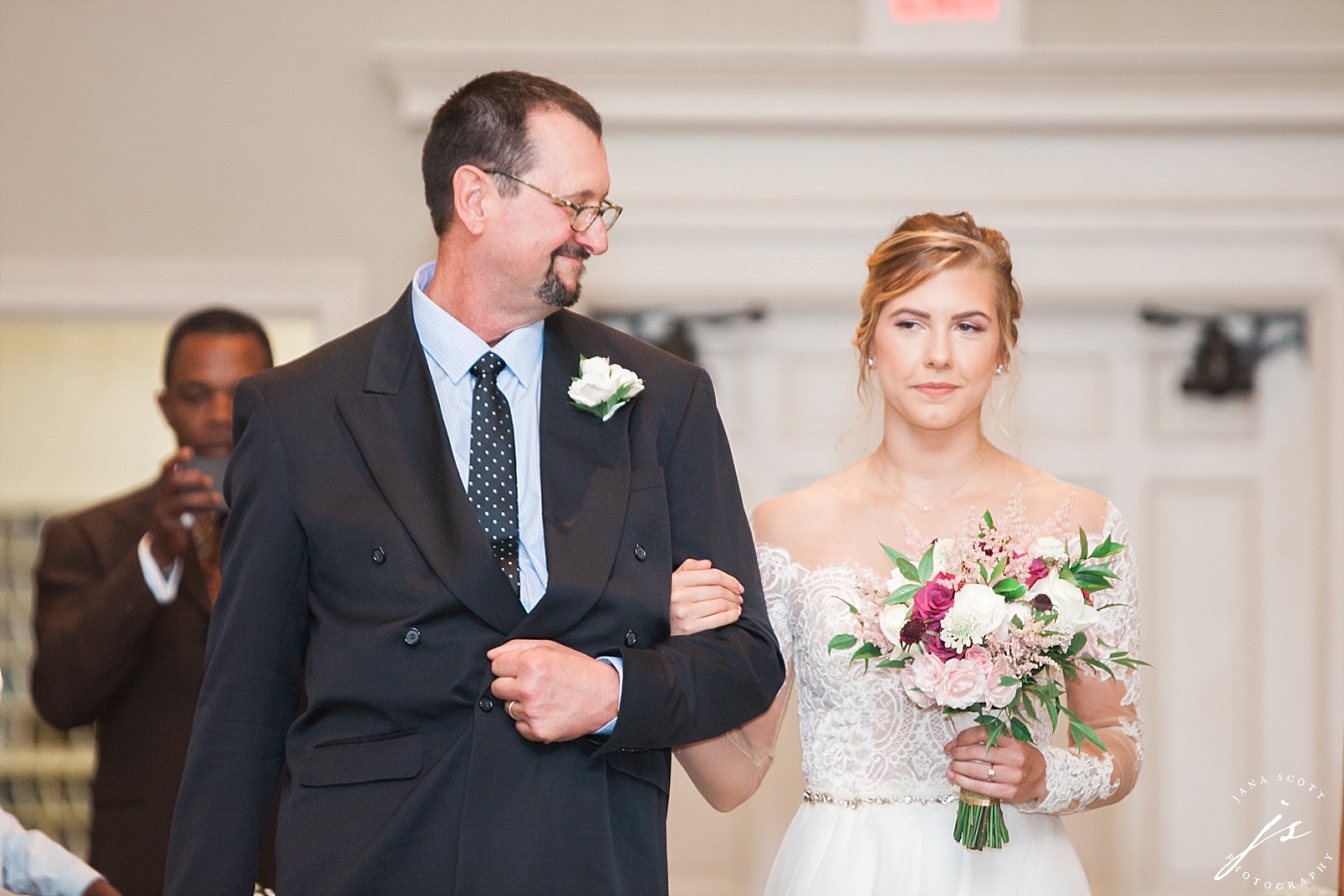 father looks at bride while walking down the aisle
