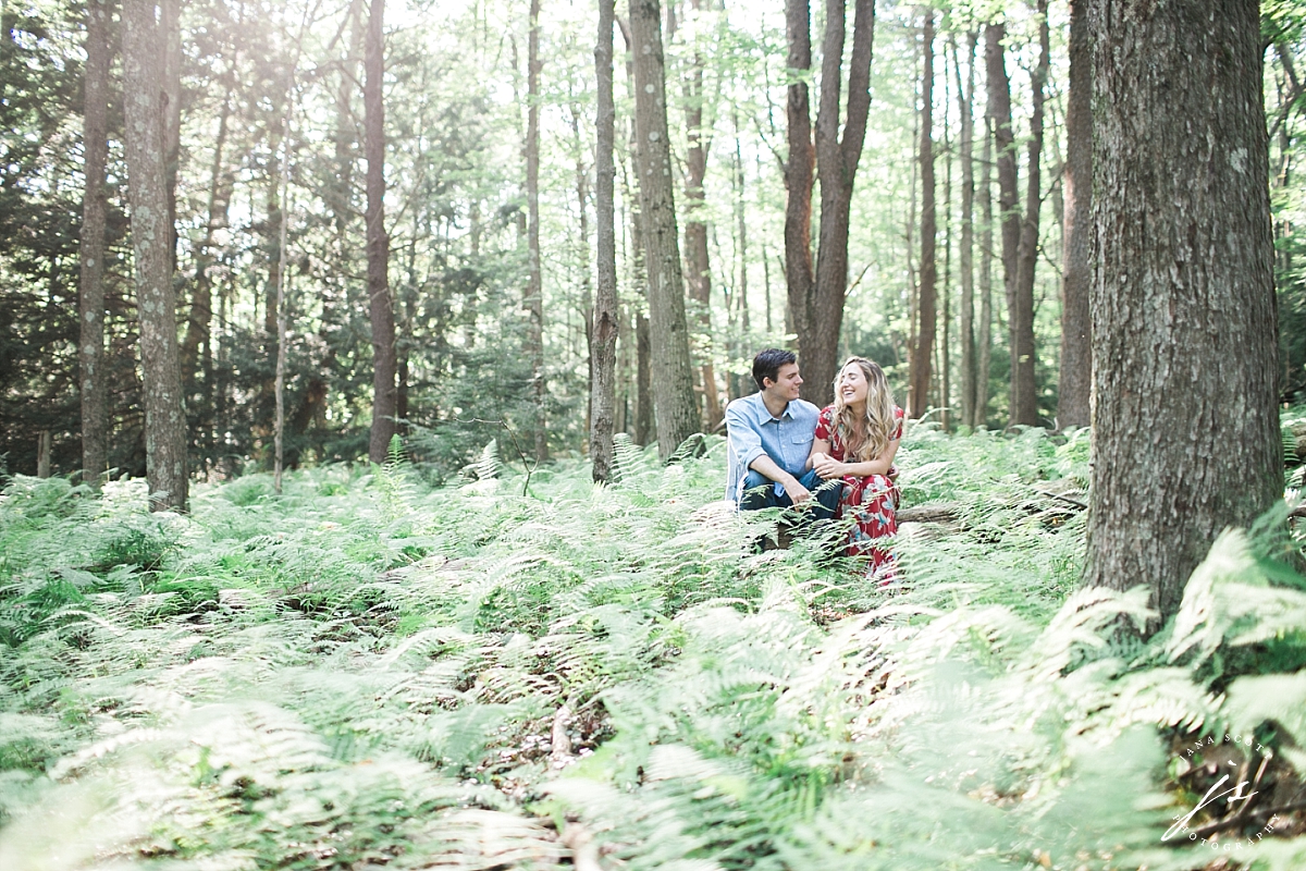 engaged couple laughs in the forest