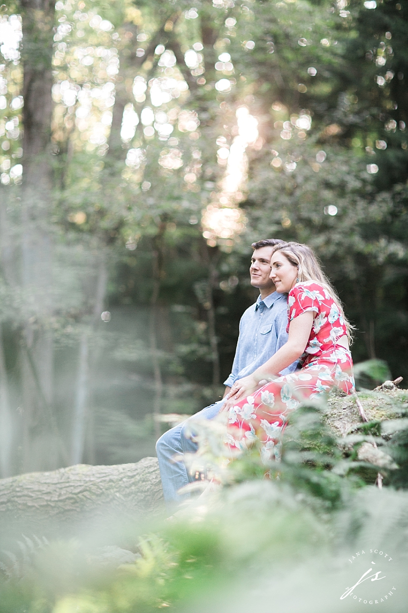 couple sits on a log in the woods