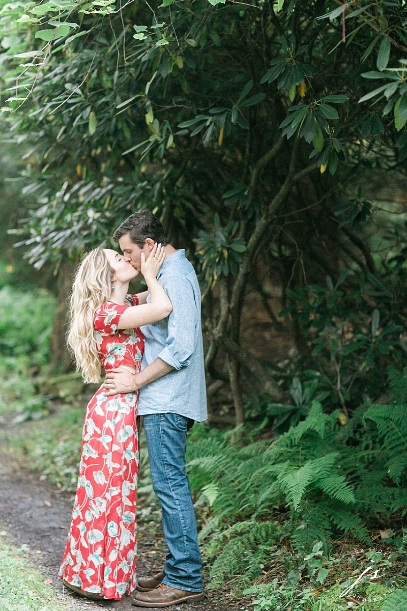 engaged couple kissing on the path