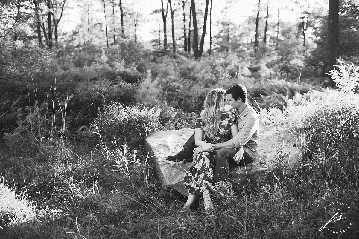 black and white of a couple sitting on a large rock