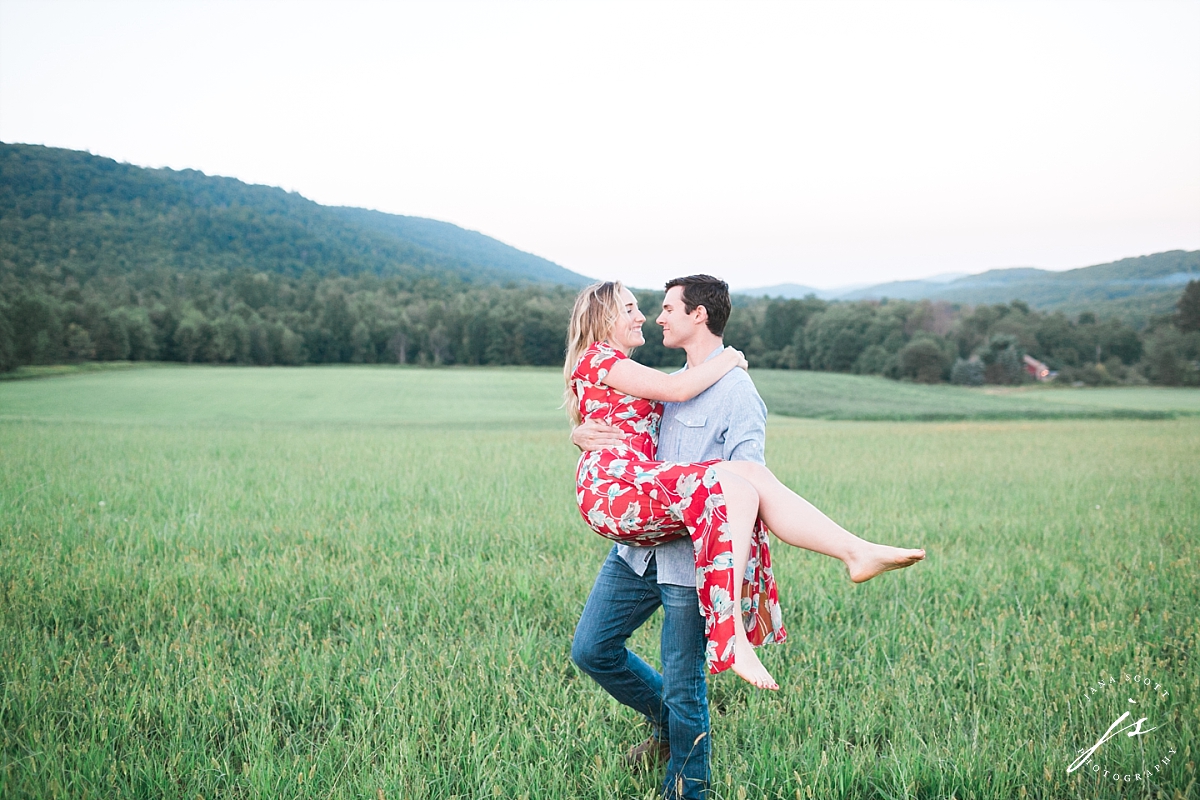 guy carrying and walking with a girl for engagement session photo in a field
