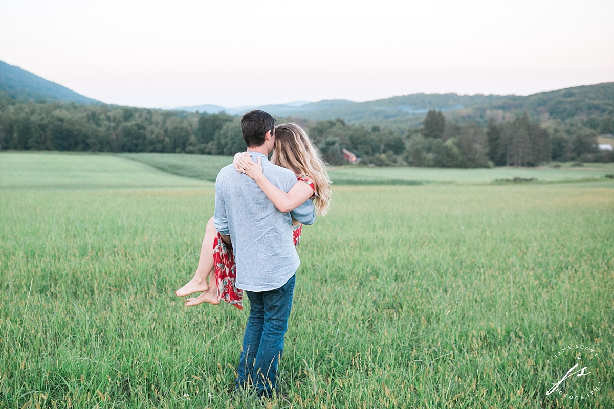 guy carries girl in a field and they look at the view together