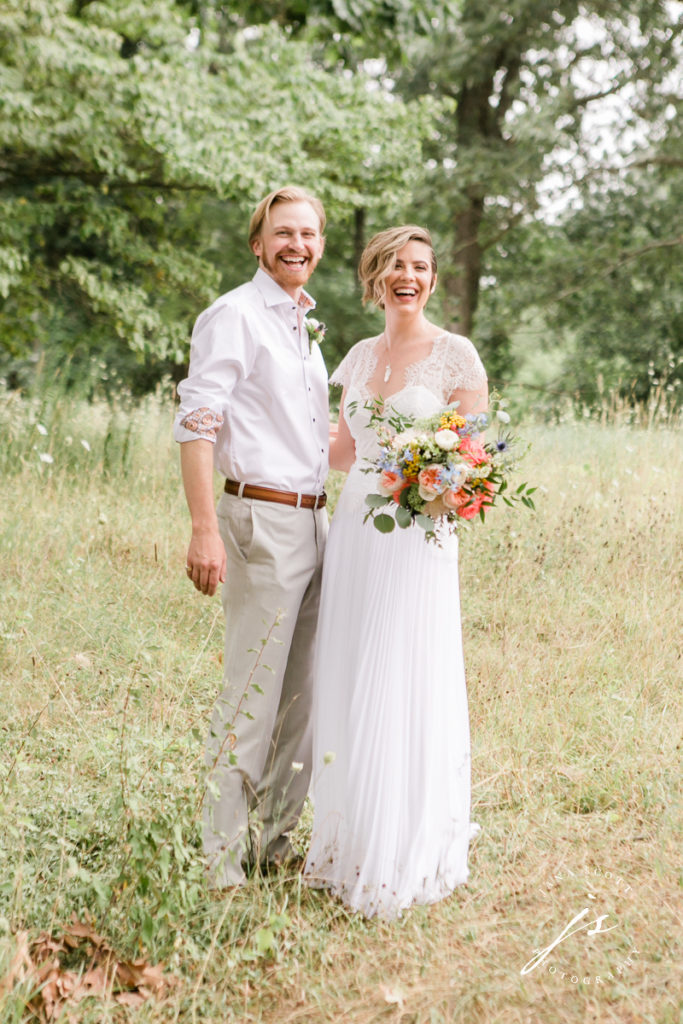 Bride and groom laughing in a field