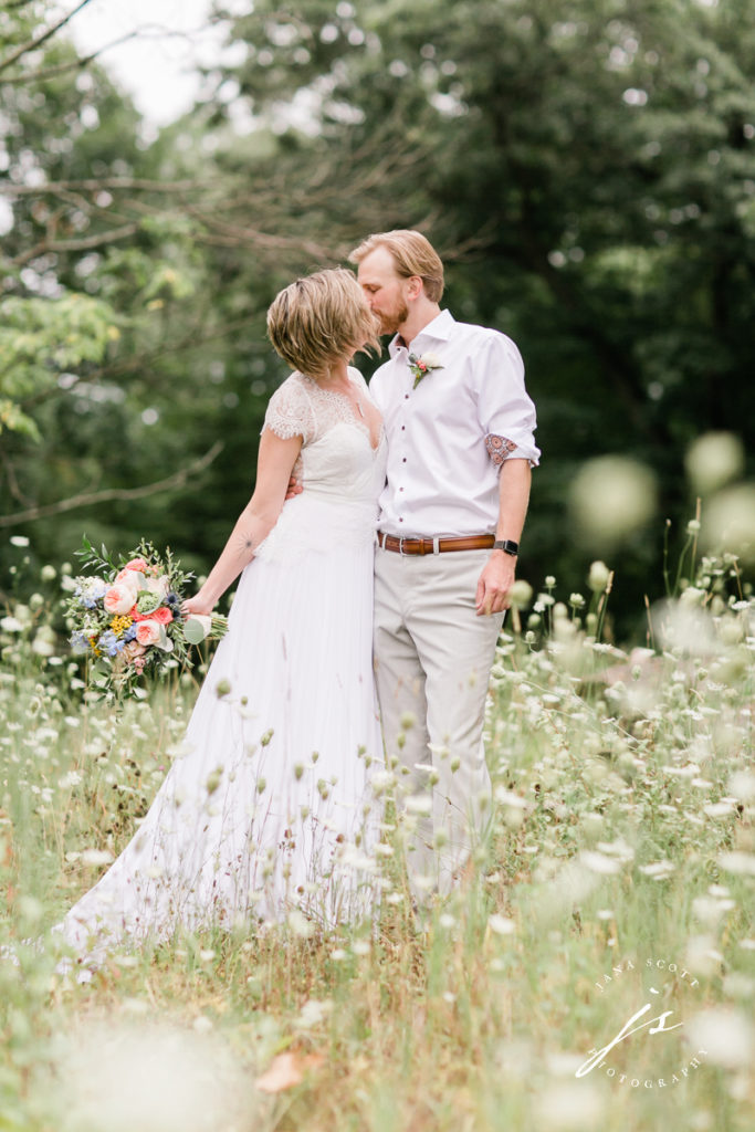bride and groom kissing in a field of queen annes lace