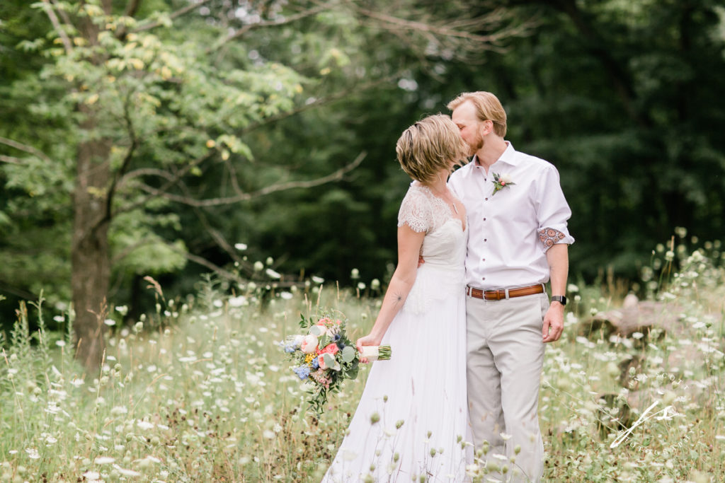bride and groom kissing in a field of queen annes lace