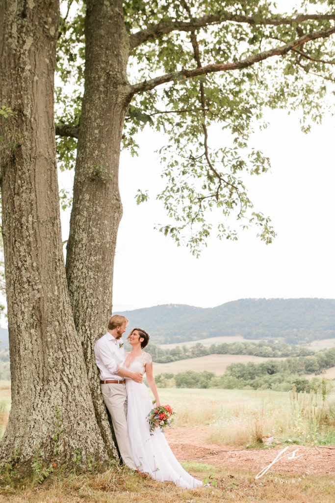 bride and groom looking at each other under a tree that looks out over a valley