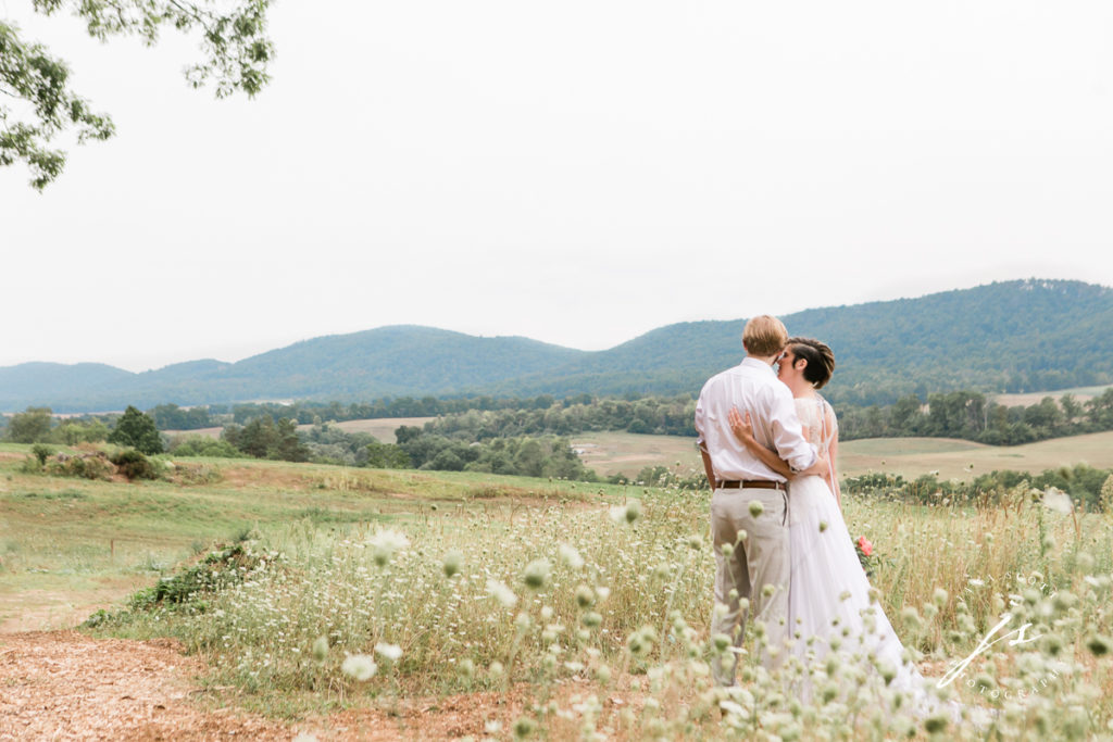Bride and groom looking out over a valley with arms holding eachother