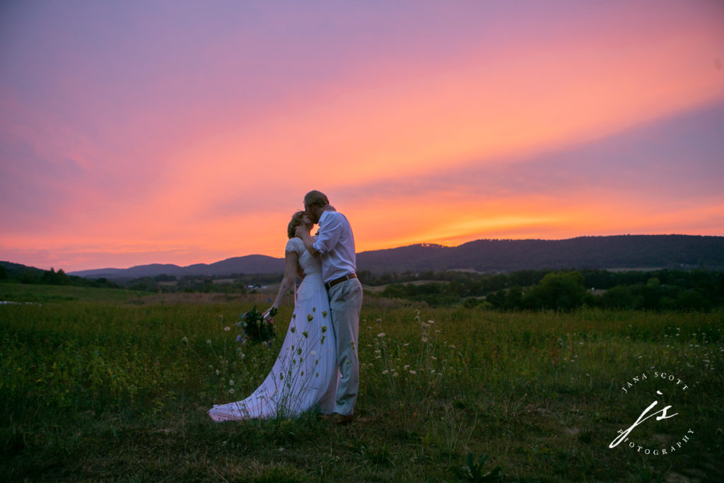 bride and groom kissing passionately at sunset