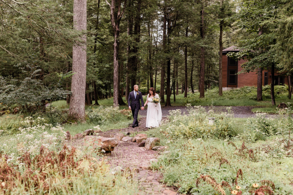 bride and groom walking on a stone path through wildflower garden