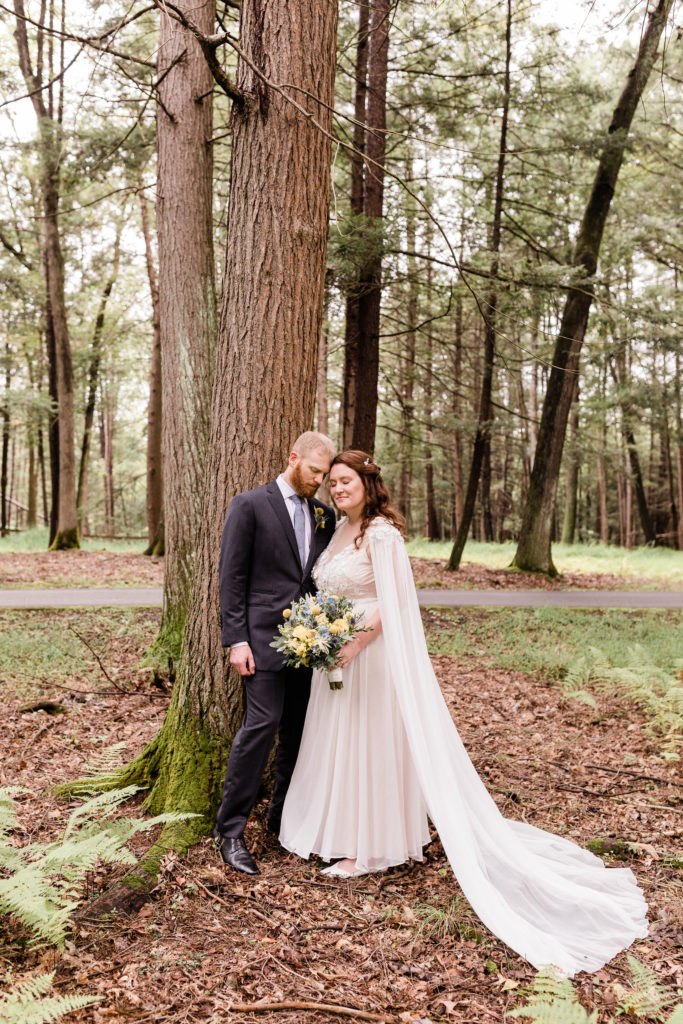bride and groom leaning on each other and a tree