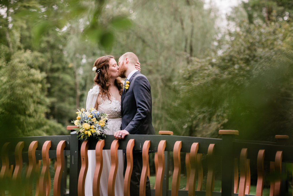 bride and groom kissing on a bridge at fern hill wedding venue