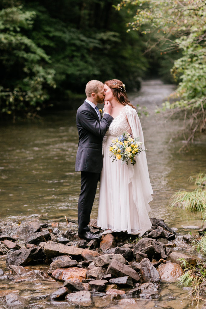 bride and groom kiss near the stream at fern hill wedding venue