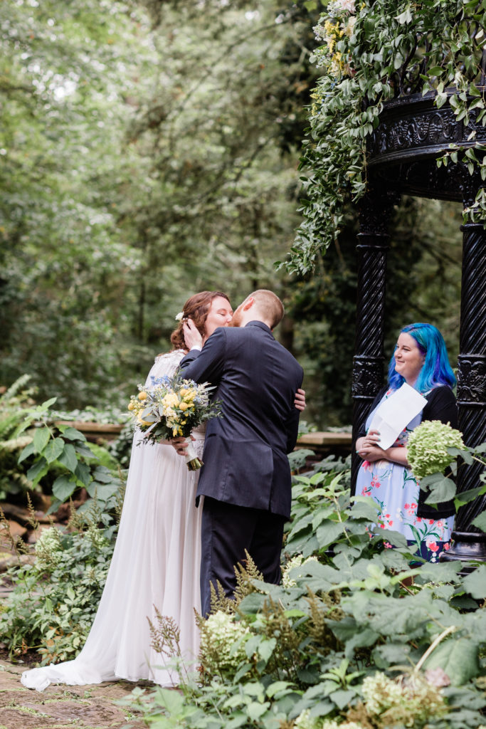 side angle of bride and groom kissing at the end of wedding ceremony